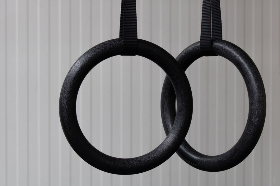 Paire d'anneaux de gymnastique noirs suspendus à leurs sangles
